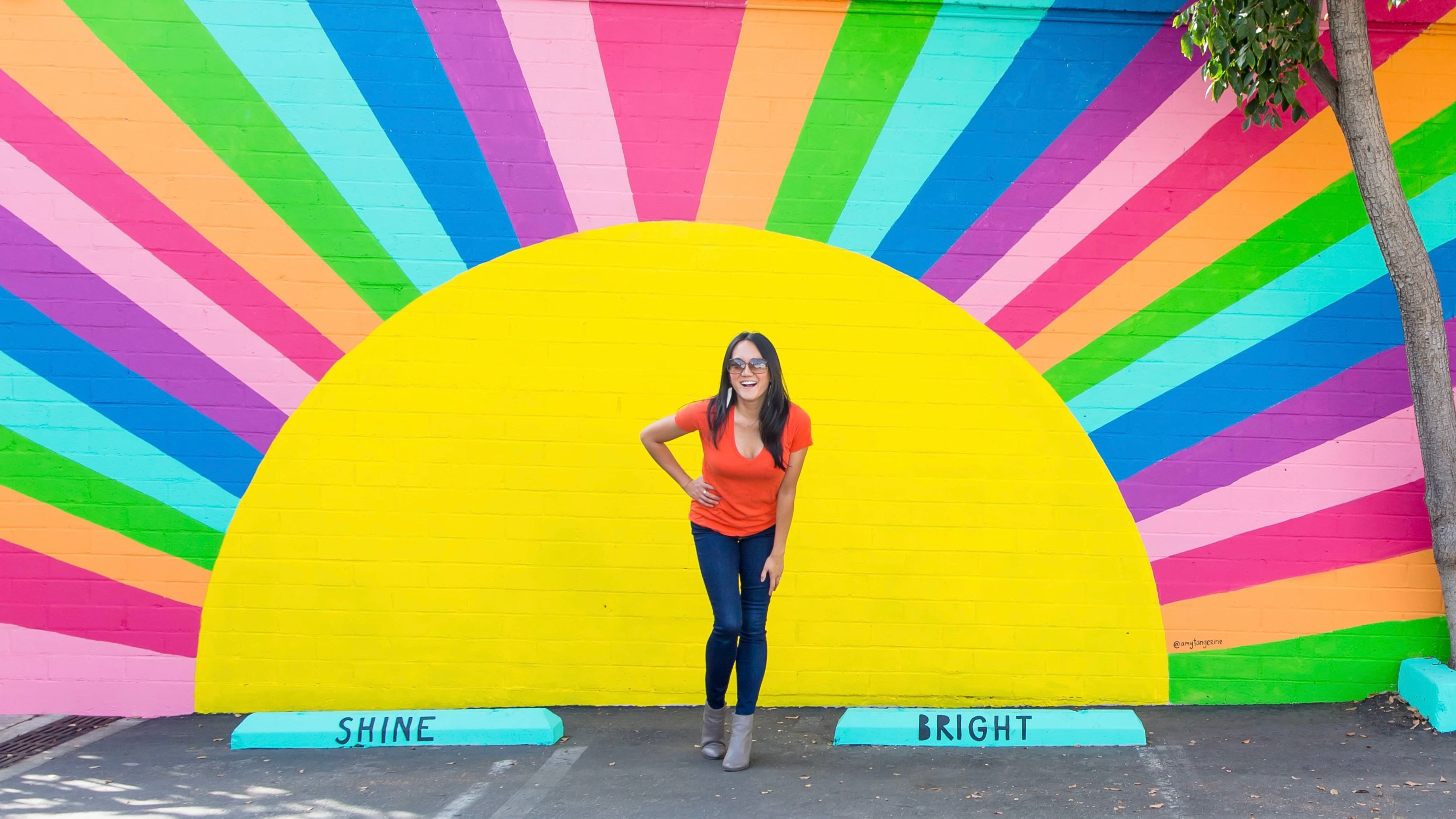 Amy in front of her Shine Bright rainbow mural (site homepage hero)